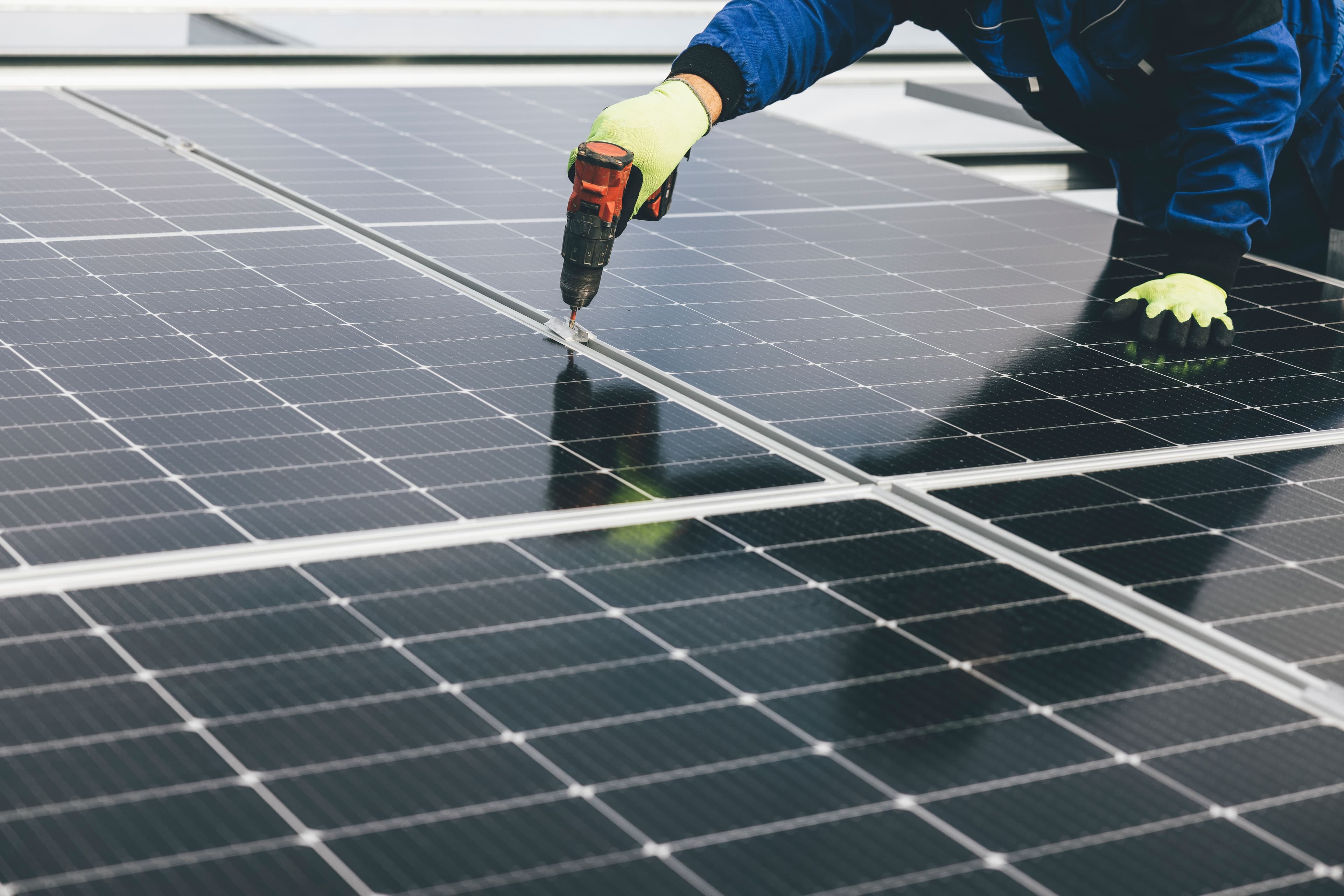 Solar technician fastening photovoltaic panels during a rooftop installation